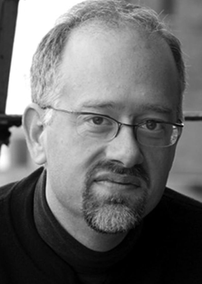 Doug Wright, playwright, wearing glasses and a goatee, looking at the camera