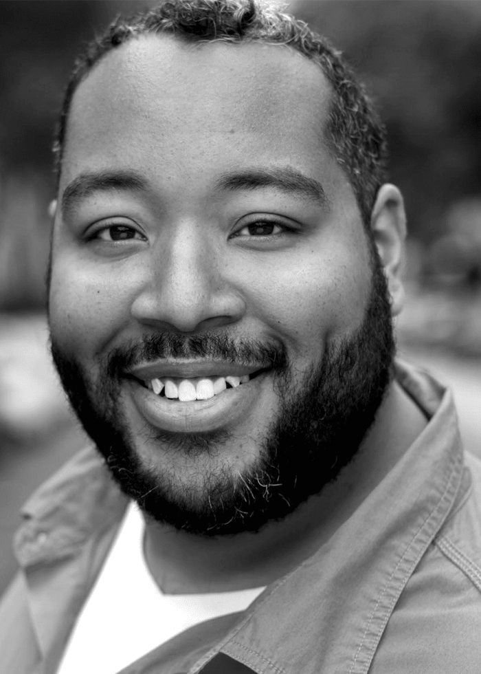 Eddie Cooper smiling, wearing a button-down shirt and beard