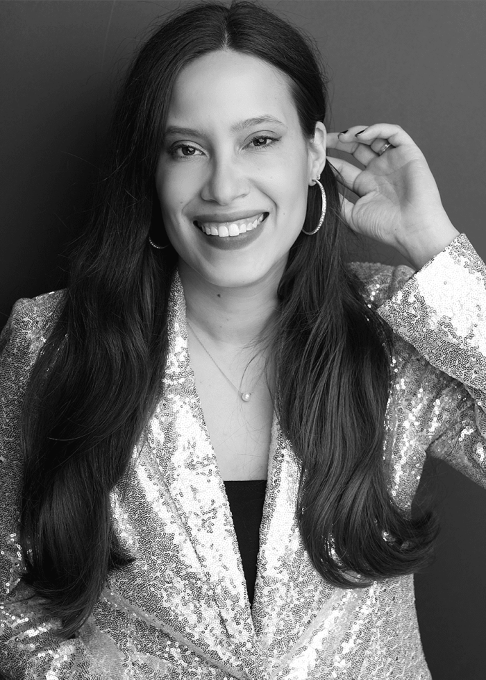 Erlina Ortiz smiling, wearing a sequined blazer and hoop earrings