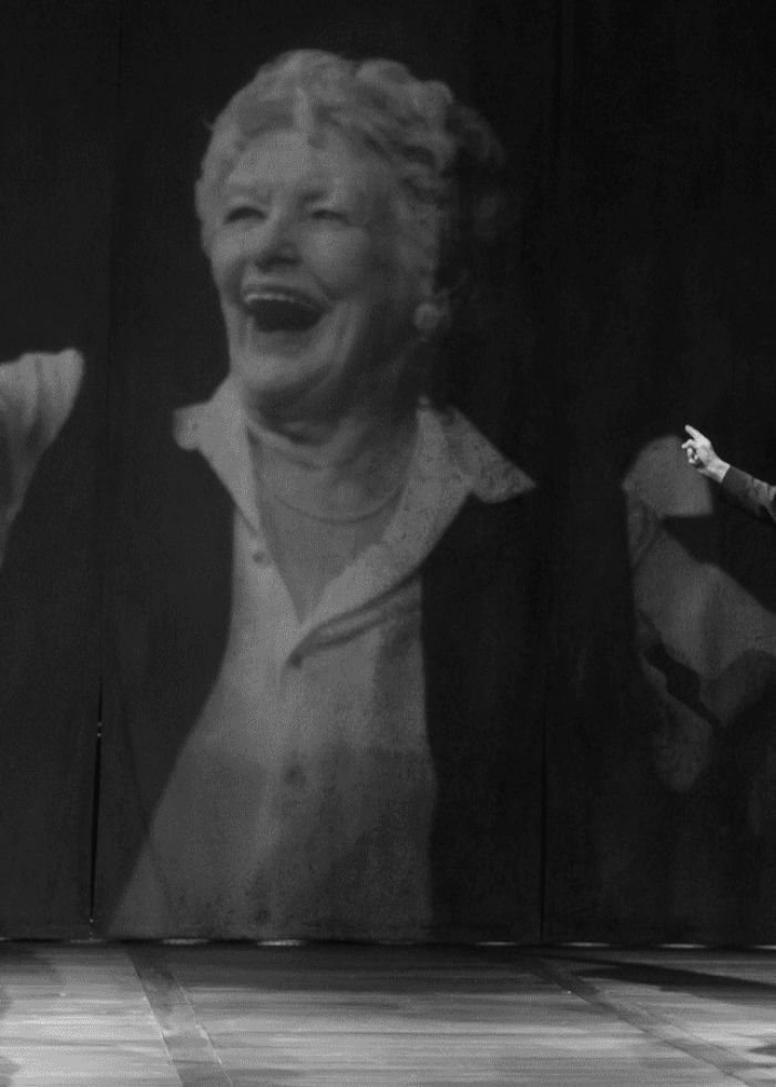 Two men on stage with a projected image of a woman, likely part of a play about memory.