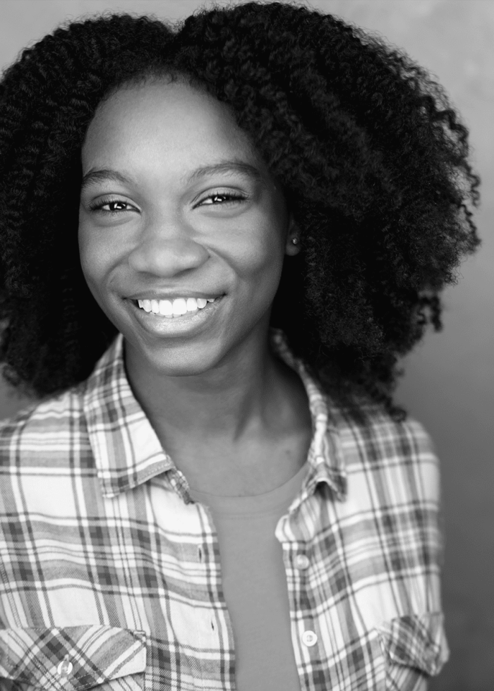 Gabriella Scott smiles in a plaid shirt, showcasing natural hair.