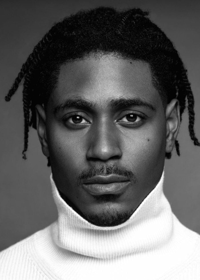 Xavier Scott Evans portrait in a white turtleneck, looking directly at the camera.