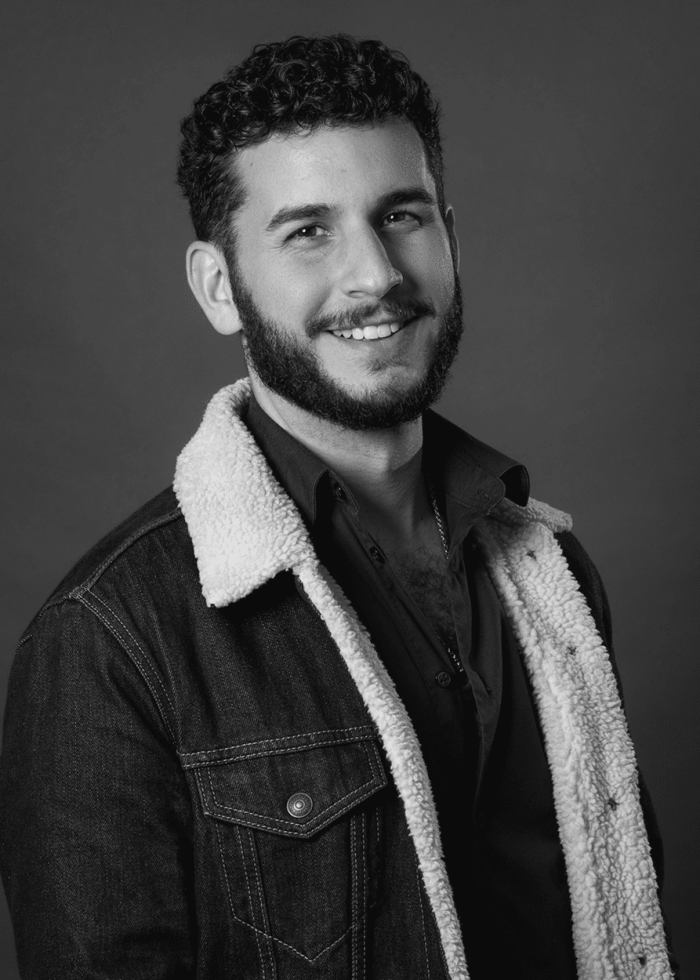 Smiling man with curly hair and beard in denim jacket with sherpa collar