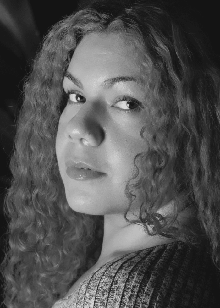 Black and white portrait of a woman with curly hair, looking over her shoulder. La Daniella.