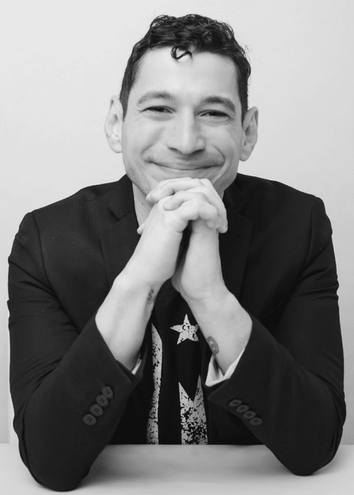 Nelson Diaz-Marcano smiling, hands clasped, wearing a t-shirt with a star.