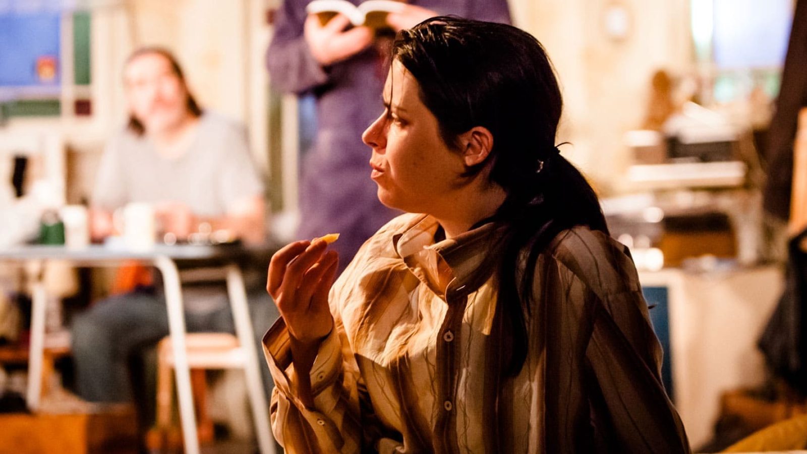 Woman eating, dimly lit room, The Night Alive
