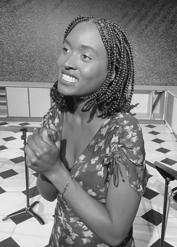 Phanésia Pharel smiling and clasping hands, wearing a floral dress.