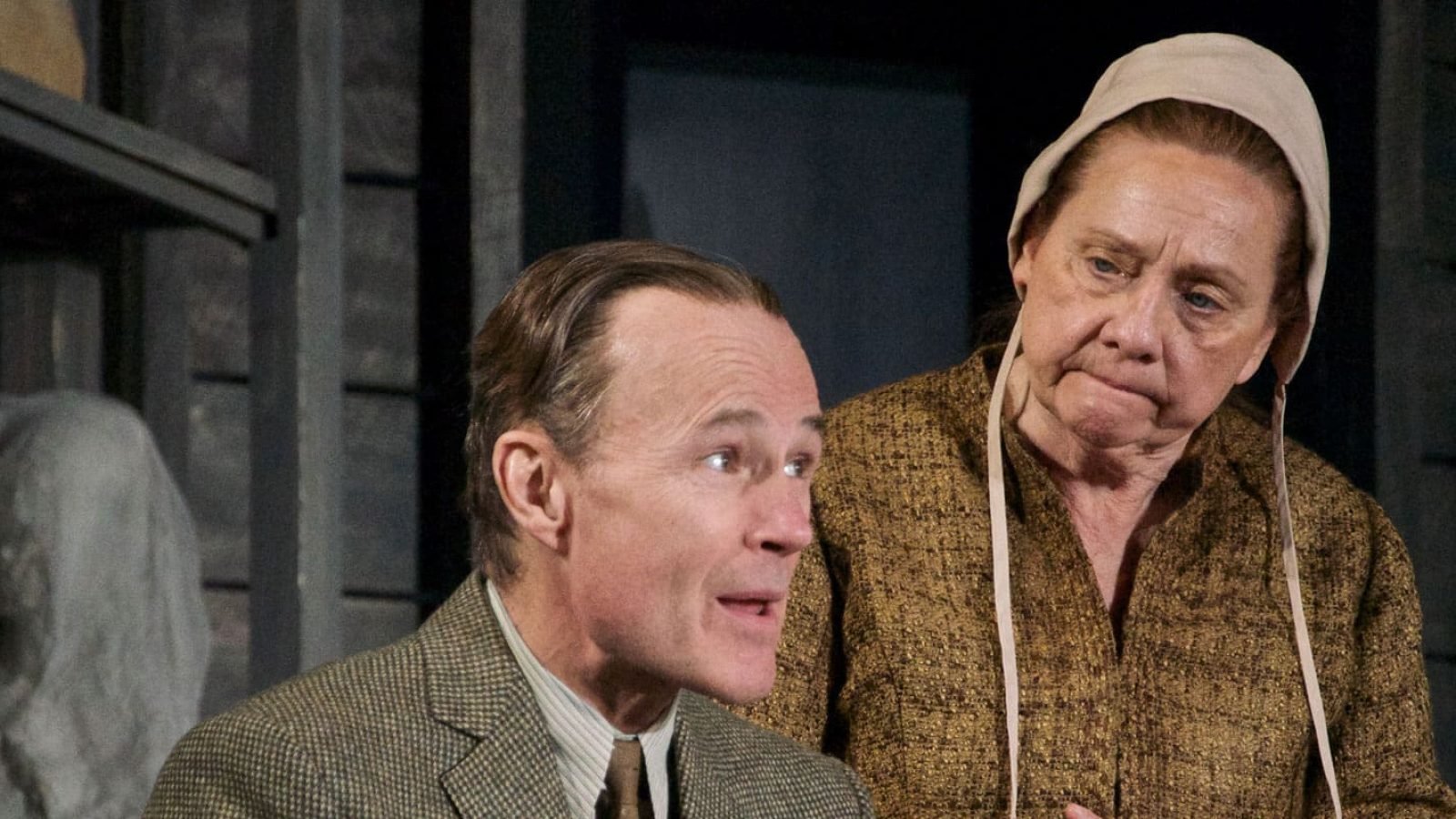 A man and woman, possibly portraying a couple, in period costume. The scene suggests a moment of quiet contemplation or conversation, hinting at themes of legacy and posterity.