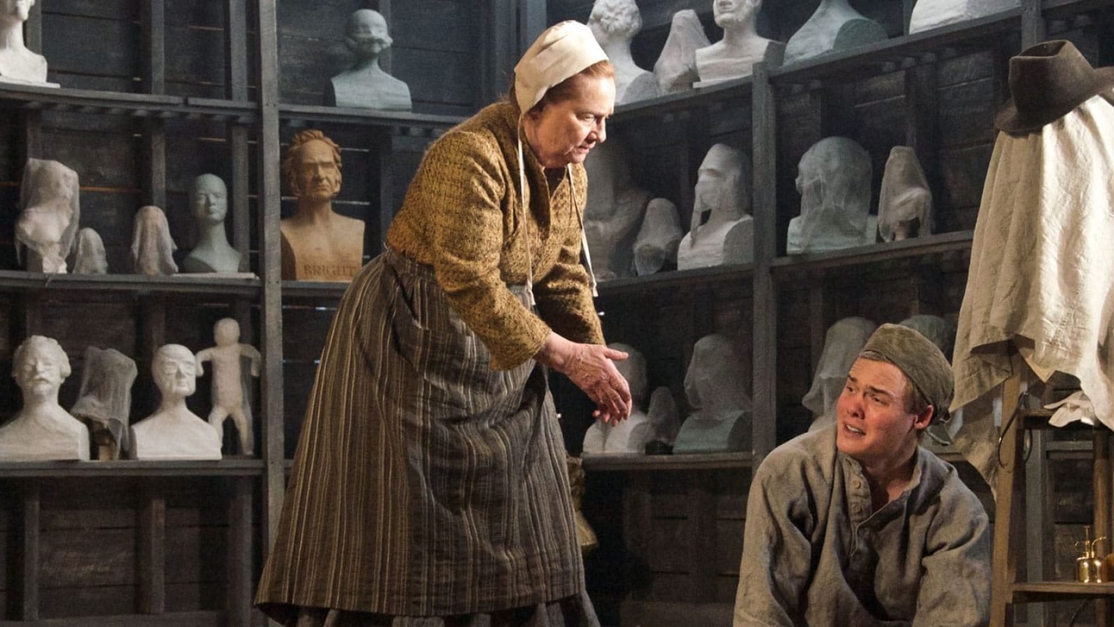 Older woman and young man in a sculptor's workshop, surrounded by plaster busts. A sense of posterity.