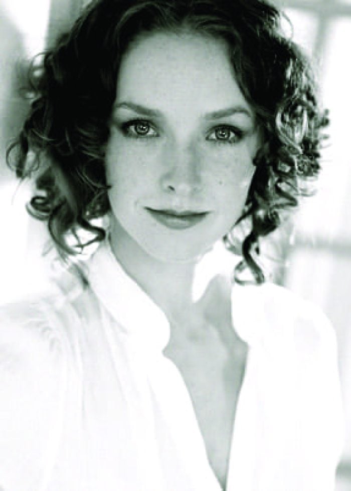 Amanda Quaid, a woman with curly hair, looks at the camera.