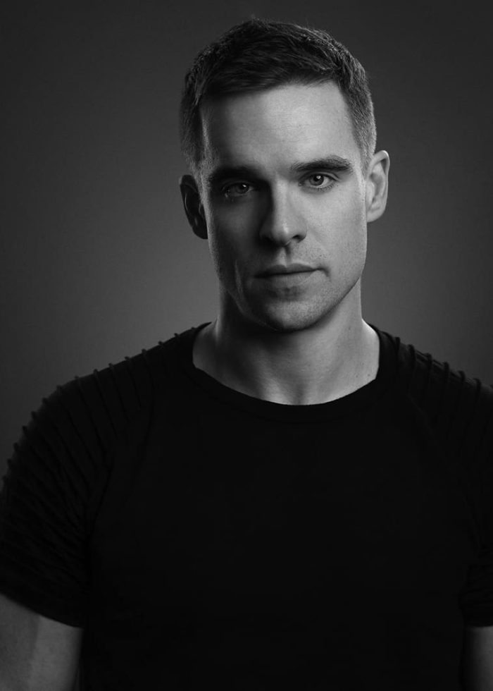 Black and white portrait of a man with short hair, gazing directly at the camera.