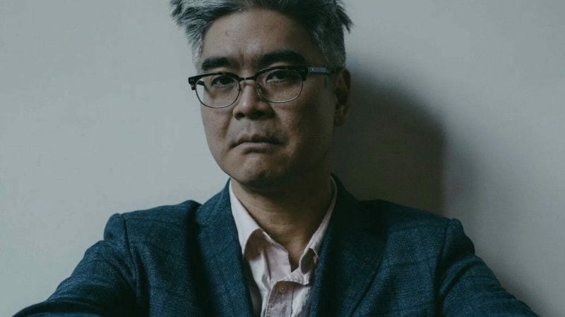 Lloyd Suh, playwright, wearing glasses and a blazer, looking directly at the camera.