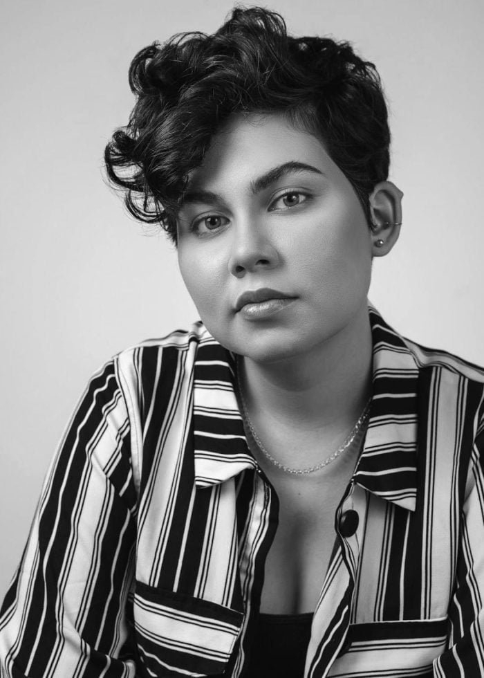 Portrait of a person with short curly hair and a striped shirt, looking at the camera.