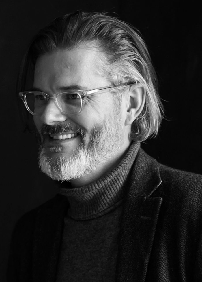 Black and white portrait of author Mo Willems smiling with glasses and a beard.