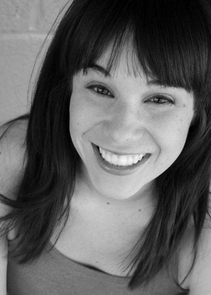 Xochitl Romero smiling directly at the camera with dark hair and bangs.